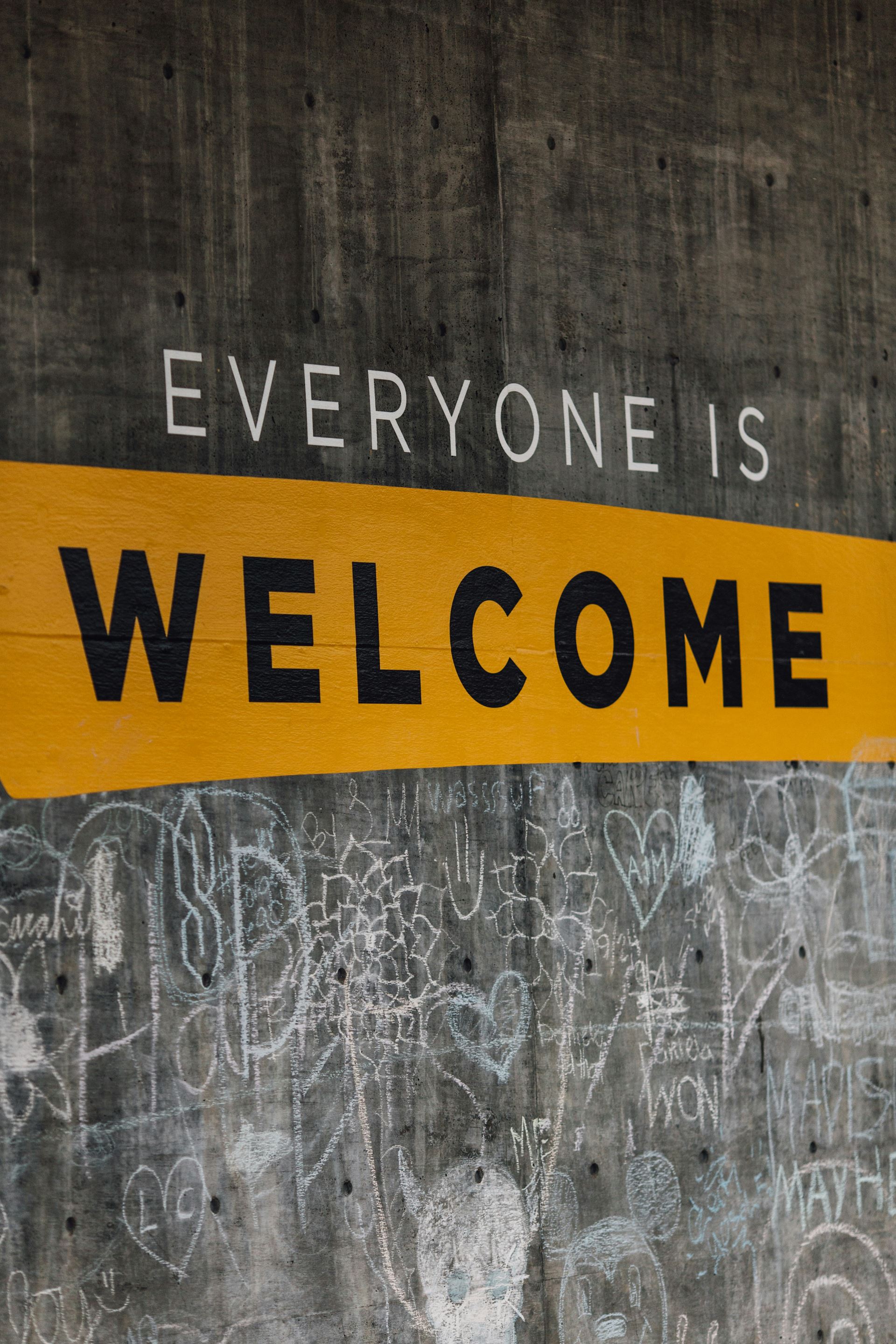 Sign saying everyone is welcome. The word Welcome is on a yellow background